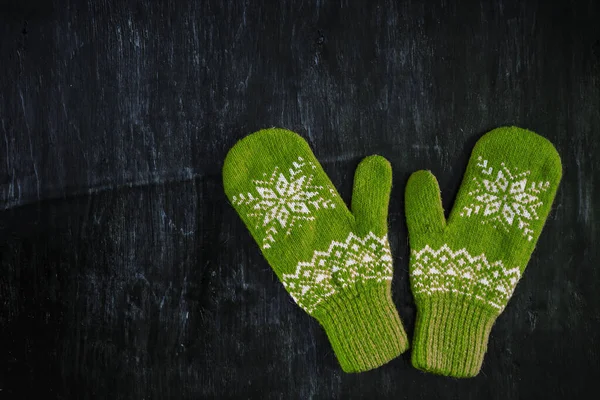 A pair of blue-green knitted mittens on a dark blue-green-brown wooden — Stock Photo, Image