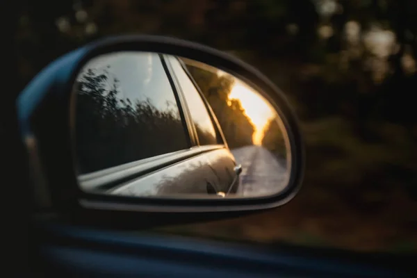 Reflektion av vägen i solnedgången solljus suddiga i sido spegeln av bilen. Närbild — Stockfoto