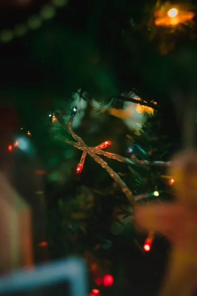 Farbig mit Lichtern eine Girlande auf einem weihnachtlich geschmückten Baum in Unschärfe, Bokeh. Nahaufnahme. — Stockfoto