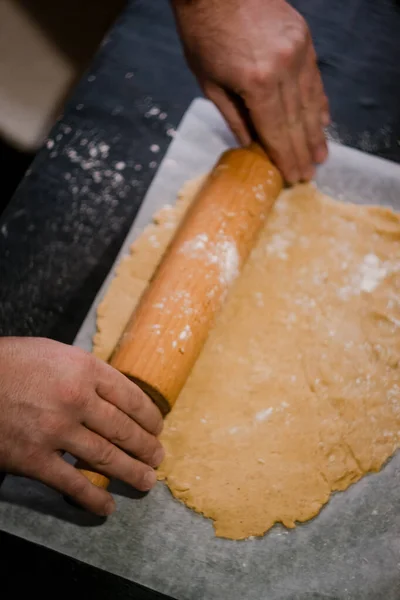 Baker's hands roll ginger dough on a dark background. Close-up, soft focus. Side view, top view. Copy space. — Stock Photo, Image