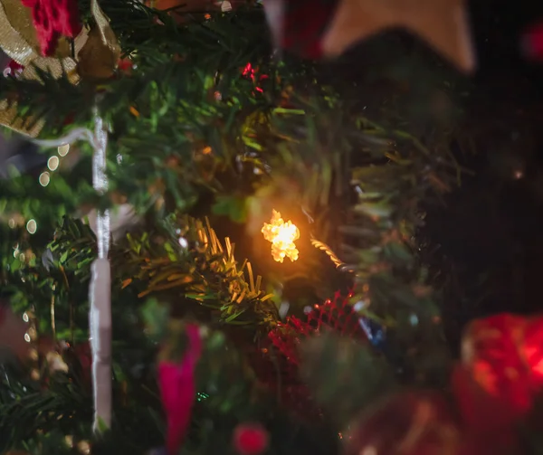 Χρωματισμένο με φώτα μια γιρλάντα σε ένα χριστουγεννιάτικο διακοσμημένο δέντρο στη θολούρα, bokeh. Κοντινό πλάνο. — Φωτογραφία Αρχείου