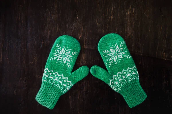 A pair of blue-green knitted mittens on a dark blue-green-brown wooden — Stock Photo, Image