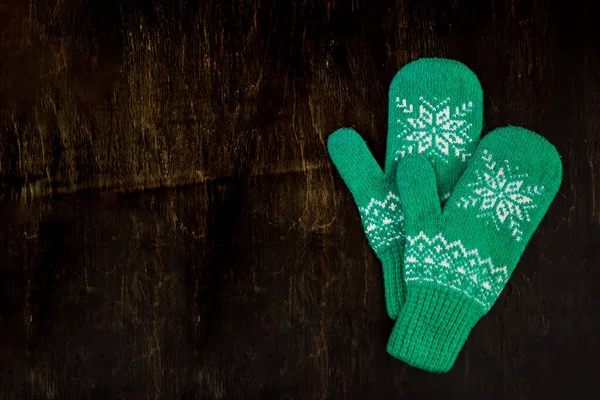 A pair of blue-green knitted mittens on a dark blue-green-brown wooden — Stock Photo, Image