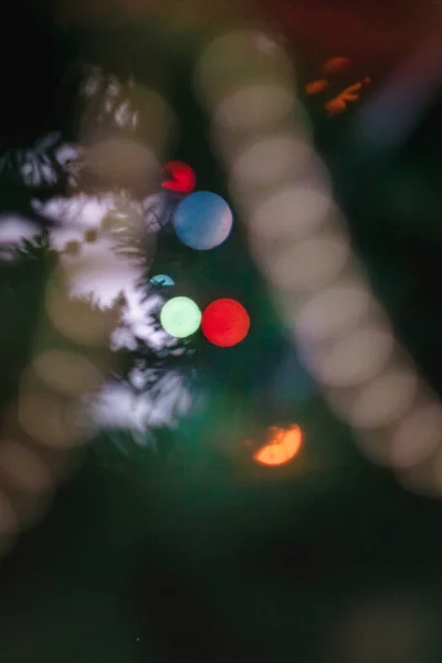 Coloreado con luces una guirnalda en un árbol decorado de Navidad en borroso, bokeh. Primer plano . —  Fotos de Stock
