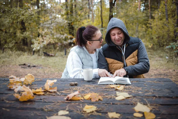 Mooi liefdevol stel zittend op de bank in het herfstpark een boek lezen, plezier hebben samen. Liefde en tederheid. Relaties, vriendschappen, onderwijs, lifestyle concept — Stockfoto