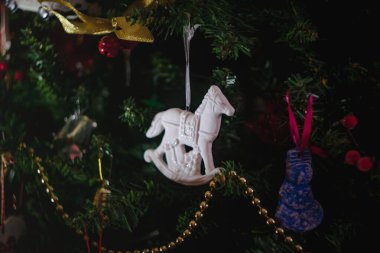 Noel oyuncakları beyaz seramik antika sallanan at şeklinde süslenmiş bir Noel ağacında hediyeler. Yakın plan..