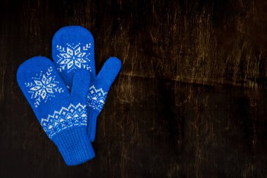 bir çift mavi örgü eldiven koyu mavi-yeşil-kahverengi ahşap üzerinde