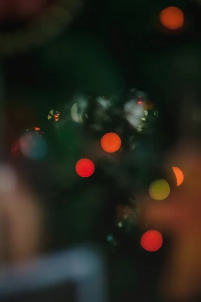 Gekleurd met lichten een bloemenslinger op een kerst versierde boom in wazig, bokeh. Close-up. — Stockfoto