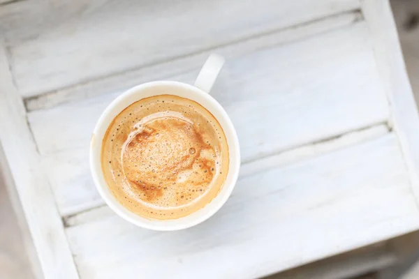 Cappuccino-Kaffee in einer Tasse auf einem weißen Holztisch. Ansicht von oben, Kopierraum. — Stockfoto