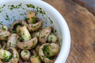 Bir kasede çiğ mantar şampiyonları salamurada otlarla birlikte, dereotlu ve sade doğal bir şekilde. Yukarıdan görüntüle