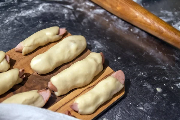 Beredda råa korvar i testet innan bakning ligger på ett bord under en servett. Koncept, husmanskost — Stockfoto