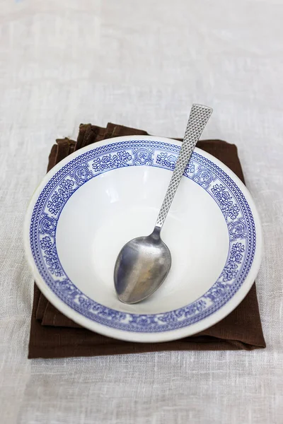 Un plato blanco profundo vacío con un patrón marroquí ruso nacional azul se encuentra en una servilleta de mantel sobre la mesa —  Fotos de Stock