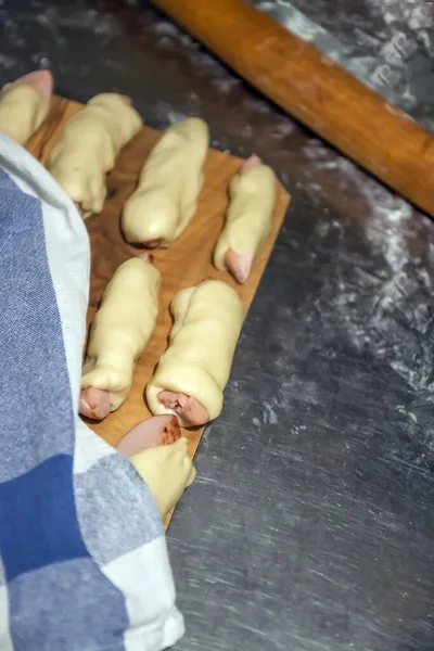 As linguiças cruas preparadas no teste antes de assar estão em uma mesa abaixo de um guardanapo. Conceito, cozinha caseira — Fotografia de Stock