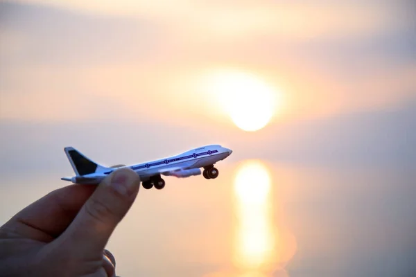 Avión de juguete en la mano contra el telón de fondo de una hermosa puesta de sol del mar. Silueta. Copiar espacio Fotos de stock libres de derechos