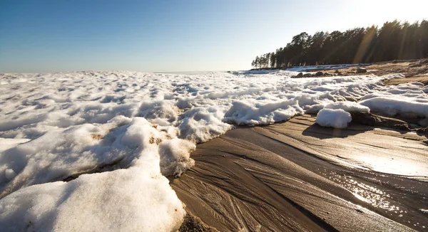 Snow pile, hill. Large snow drift isolated on a blue sky background, outdoor view of ice blocks at frozen finland lake in winter