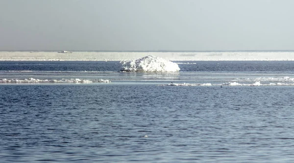 Snow pile, hill. Large snow drift isolated on a blue sky background, outdoor view of ice blocks at frozen finland lake in winter