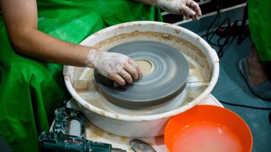 Bir çömlekçinin elinde çiğ kil bir tencere. Çömlek atölyesinde atölye. Çömlekçi tekerleğinde kil çömlek