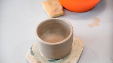 Bir çömlekçinin elinde çiğ kil bir tencere. Çömlek atölyesinde atölye. Çömlekçi tekerleğinde kil çömlek