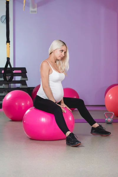 Mujer embarazada en el gimnasio sentada en la pelota relajándose después del entrenamiento para mantenerse en forma — Foto de Stock