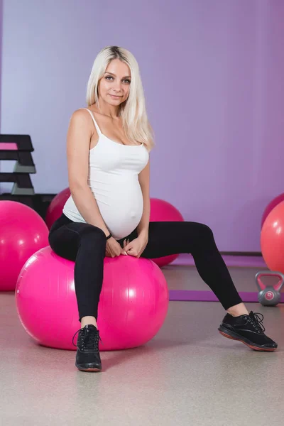 Mujer embarazada en el gimnasio sentada en la pelota relajándose después del entrenamiento para mantenerse en forma — Foto de Stock