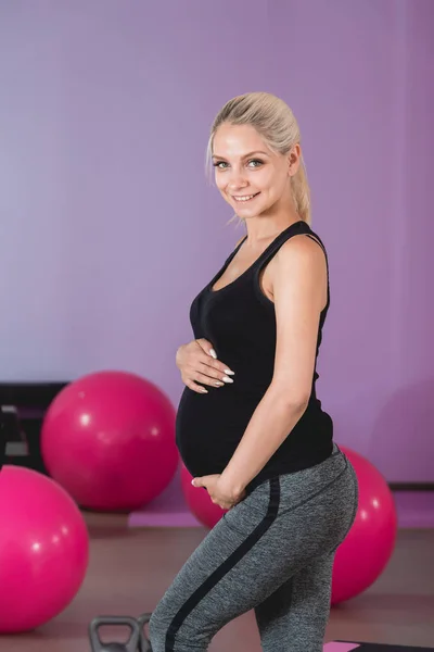 Mujer embarazada de pie en el gimnasio, sosteniendo su vientre en 9 meses con hermosa vista — Foto de Stock