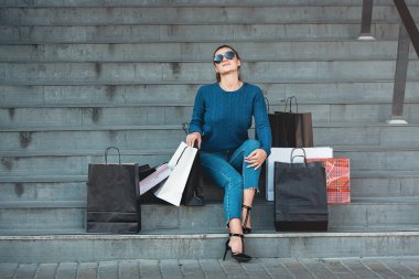 Kağıt torba ile güzel kız bir merdiven alışveriş merkezi dışında oturur