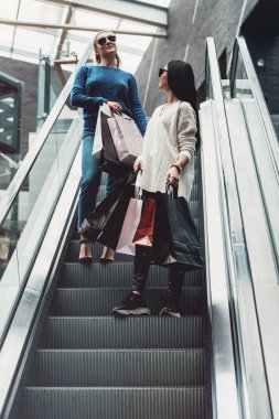 Kağıt poşet süpermarkette yürüyen merdiven üzerinde güzel kızlarla