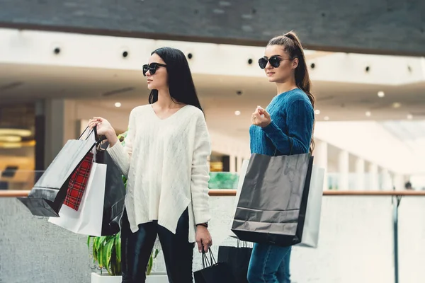 Beautiful girls with paper bags in a hall of a shopping mall — Stock Photo, Image