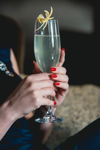 Franch cocktail in womans hands with red manicure. Luxery hotel lobby bar. Dark blu dress — Stock Photo, Image