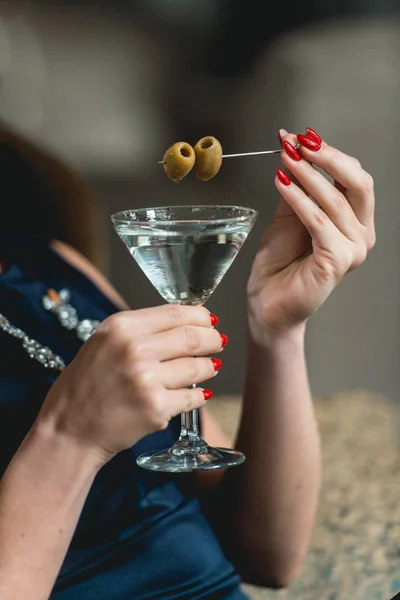 Dry Martini cocktail in womans hands with red manicure. Luxery hotel lobby bar. — Stock Photo, Image