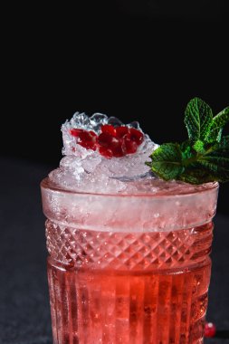 Soğuk buz ve garnet tohumları, koyu arka plan üzerinde nar parçası ile kokteyl