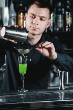 barmen yeşil alkollü kokteyl bardağına sıvı dökme yapma.