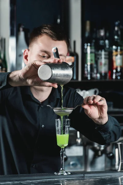 酒保, 使绿色酒精鸡尾酒将液体浇注到玻璃中. — 图库照片