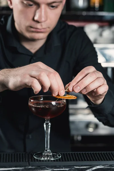 Boulevardier 칵테일 마무리 위에 오렌지 슬라이스 퍼 팅 칵테일 만드는 바텐더. 배경에 바 — 스톡 사진