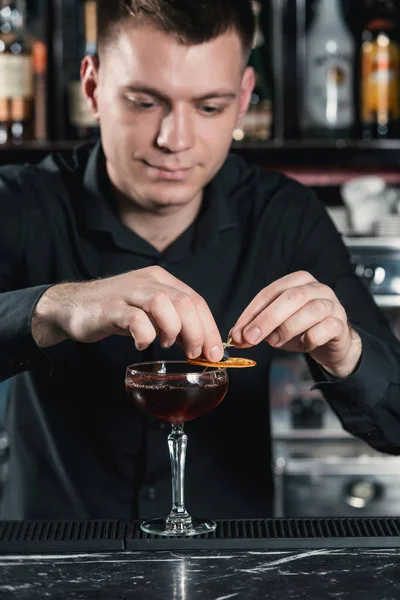 Camarero haciendo Boulevardier Cocktail Acabado cóctel poner rebanada de naranja en la parte superior. Bar sobre fondo — Foto de Stock