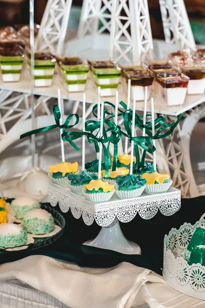 绿色风格的婚礼糖果棒上的白色桌子。用绿色丝带蝴蝶结装饰的纸杯蛋糕 — 图库照片