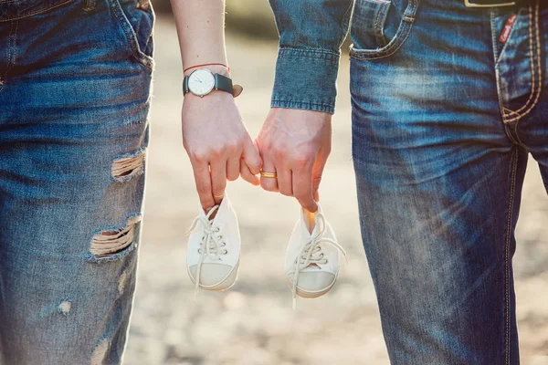 Young pregnant couple holding newborn baby shoes family and parenthood concept — Stock Photo, Image