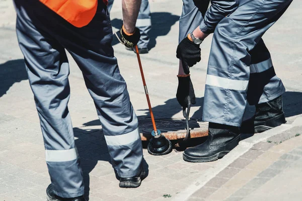 Two workers of emergency gas service, checking concentration of gas in the sewer