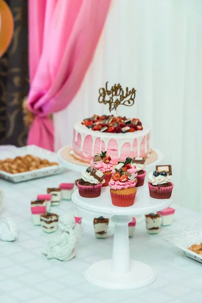 Soporte blanco con cupcakes en una mesa de barra de caramelo — Foto de Stock
