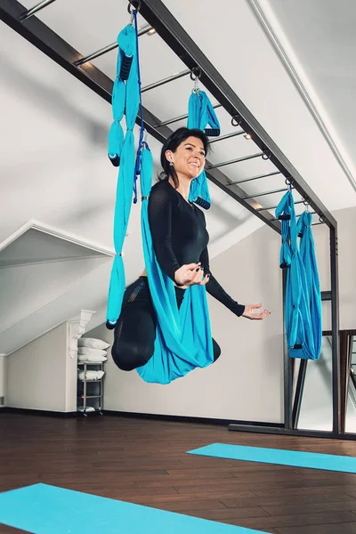 Yoga en una habitación blanca. mujer realiza ejercicios físicos fly-yoga, pilates en un equipo especial — Foto de Stock