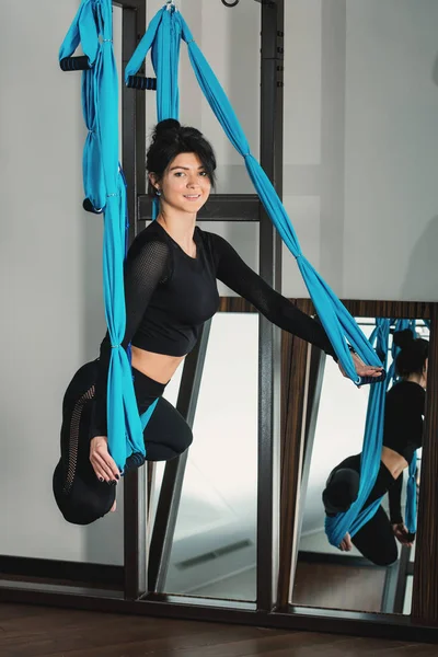 Yoga en una habitación blanca. mujer realiza ejercicios físicos fly-yoga, pilates en un equipo especial — Foto de Stock