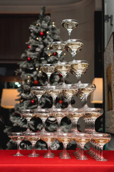 Champagne toren op een rode tafel met kerstboom op de achtergrond — Stockfoto
