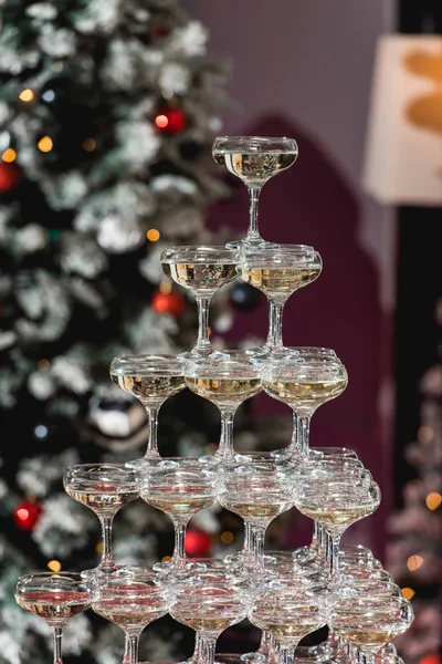 Champagne tower on a red table with Christmas tree in the background