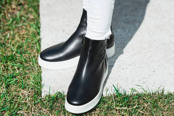 Top View Of Woman's Black Leather Ankle Boots. Outdoor Shot Over White Stone in park