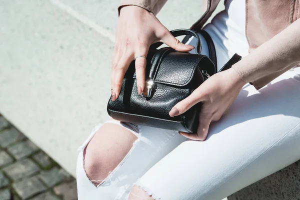 Las manos de las mujeres abren una bolsa de cuero negro — Foto de Stock