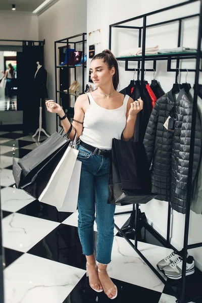 Smiling girl doing many purchases at the clothing shop. Woman with packeges in hands in a clothing boutique — Stock Photo, Image