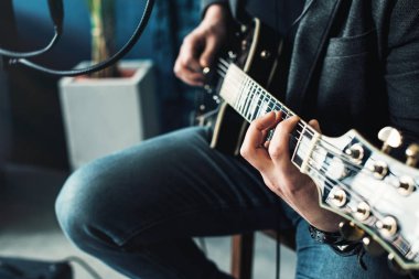Bir ev stüdyosunda bir parça kayıt gitar ile kulaklık bir taburede oturan bir adam şarkıcı yakın