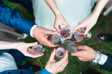 İnsanlar ellerinde kırmızı şarapla bardak tutarlar. düğün partisi.