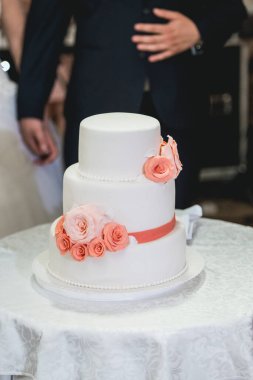 Düğün töreni. Gelin ve damat ilk davalarını birlikte yapıyorlar. Çiçekle süslenmiş güzel düğün pastasını kesiyorlar.