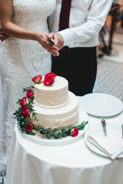 Düğün töreni. Gelin ve damat ilk davalarını birlikte yapıyorlar. Çiçekle süslenmiş güzel düğün pastasını kesiyorlar.